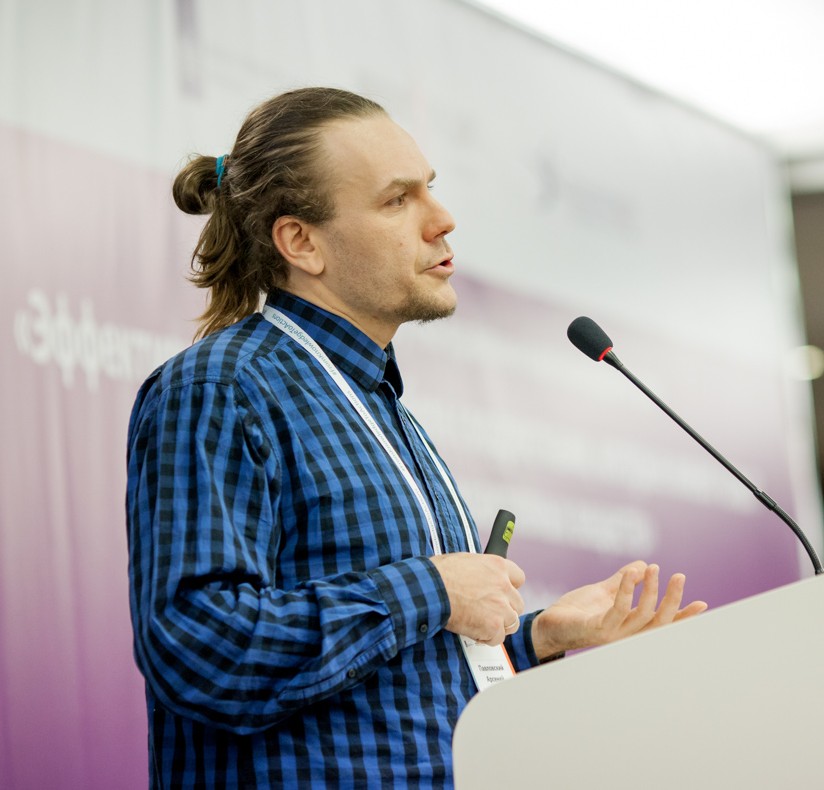 Arsenijs Pavlovskis runā no tribīnes konferences laikā, viņš ir ģērbies zilā rūtainā kreklā.